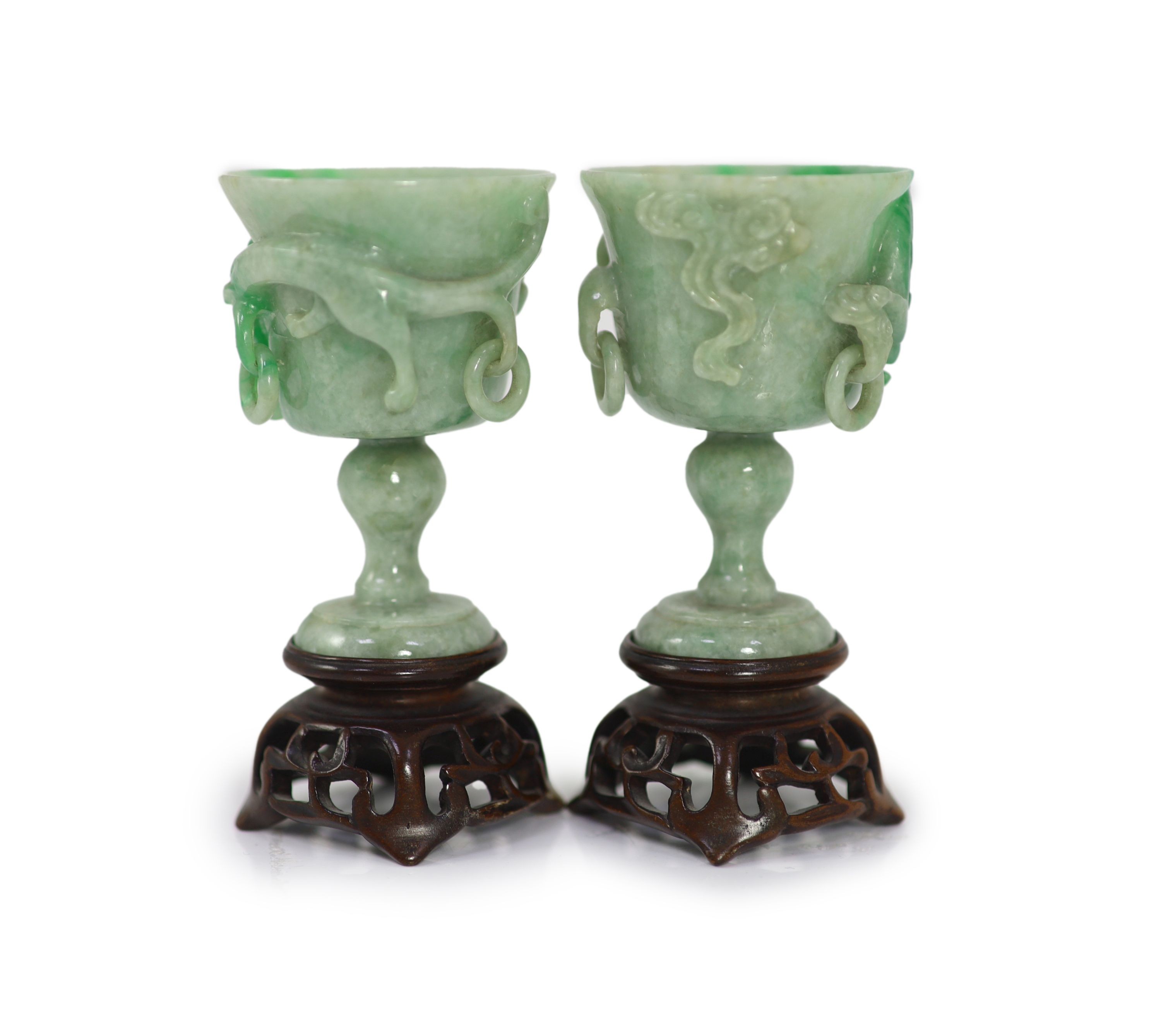 A pair of Chinese small jadeite stem cups, 20th century, 7.2cm high, carved wood stands